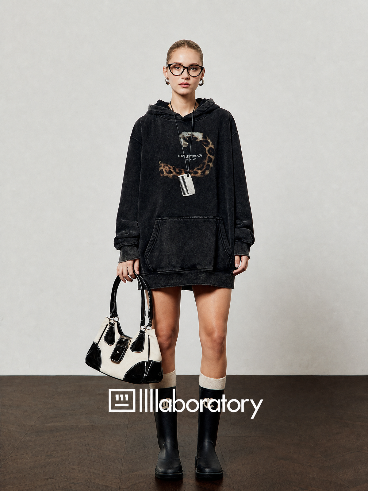 European blonde woman wearing the vintage black fleece hoodie with original text and leopard-tail graphic