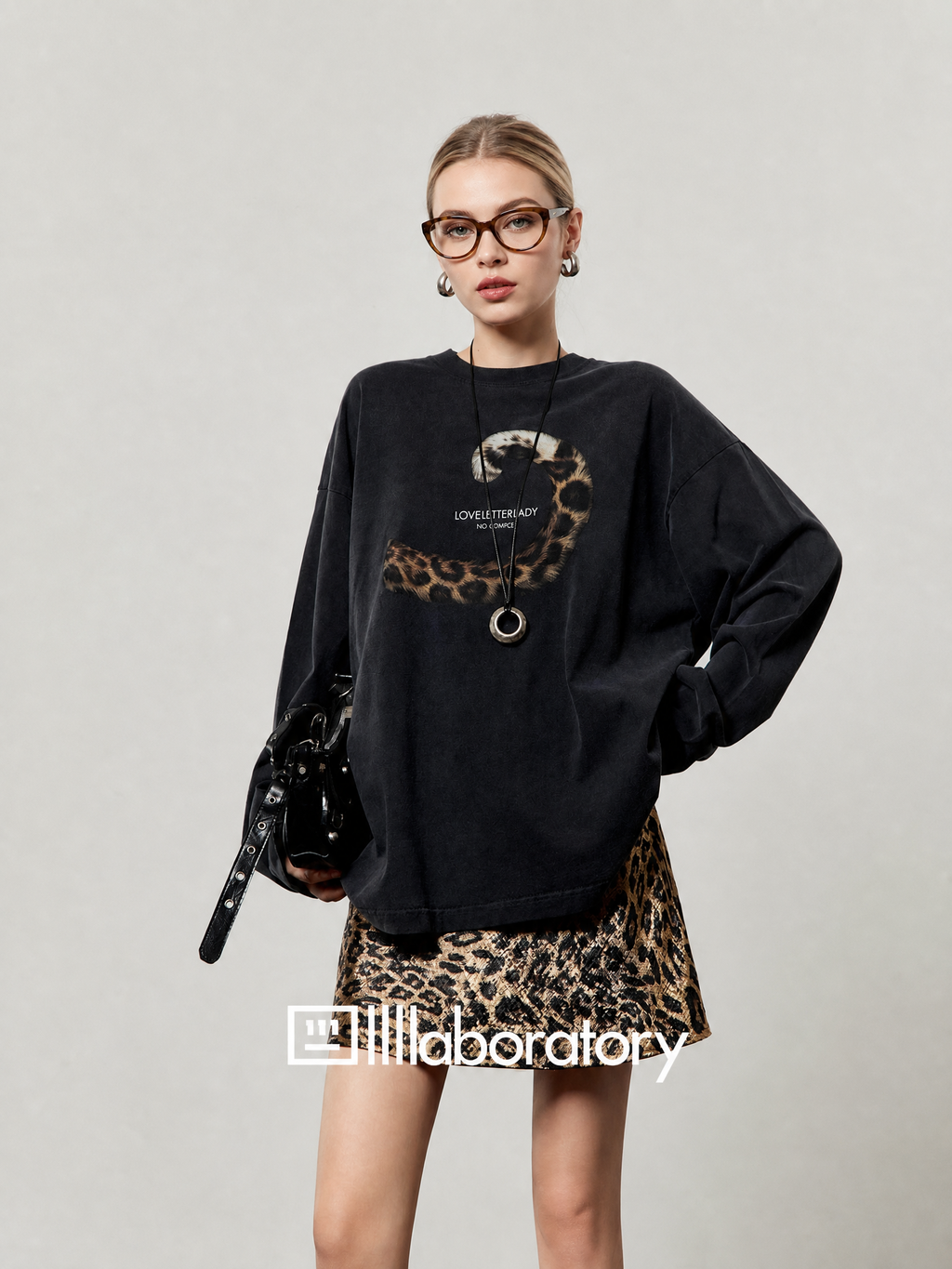 European female model in black leopard-tail long-sleeve top with original text graphic visible