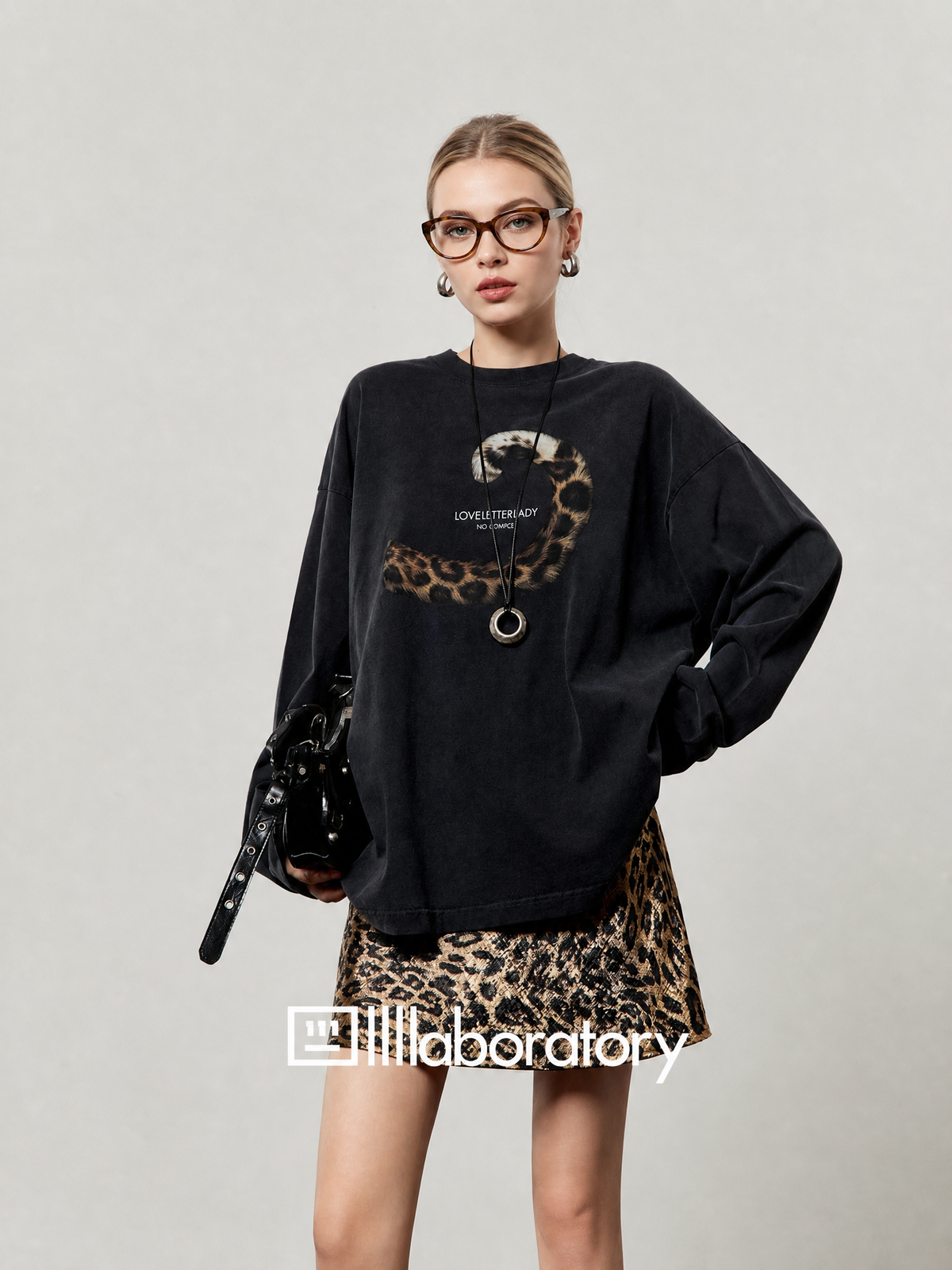 European female model in black leopard-tail long-sleeve top with original text graphic visible